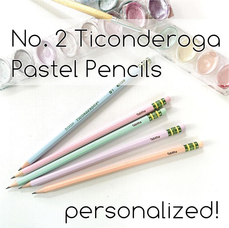 A collection of pastel-colored Ticonderoga pencils with personalized engravings, displayed alongside a transparent case filled with additional pencils in the background.
